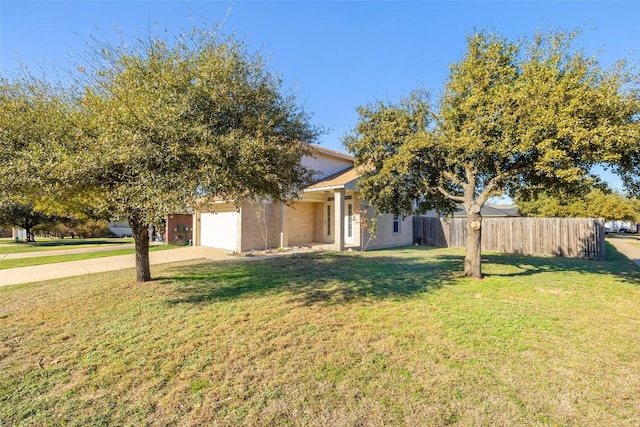 view of property hidden behind natural elements featuring a garage and a front lawn