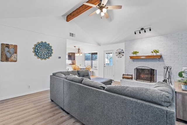 living room featuring a fireplace, lofted ceiling with beams, ceiling fan with notable chandelier, and light hardwood / wood-style floors