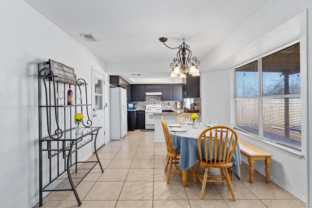 tiled dining room featuring sink and a notable chandelier