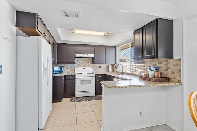 kitchen featuring kitchen peninsula, decorative backsplash, white appliances, a raised ceiling, and sink