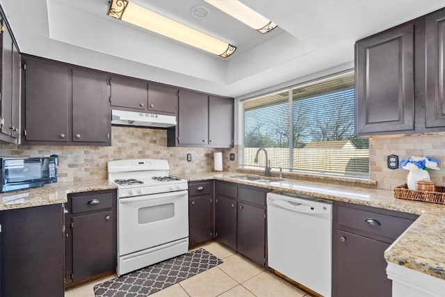 kitchen with white appliances, sink, light tile patterned floors, and a tray ceiling