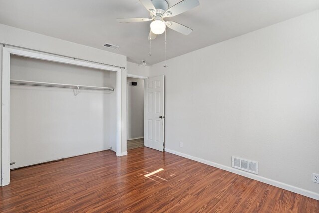 unfurnished bedroom featuring dark hardwood / wood-style flooring, ceiling fan, and a closet