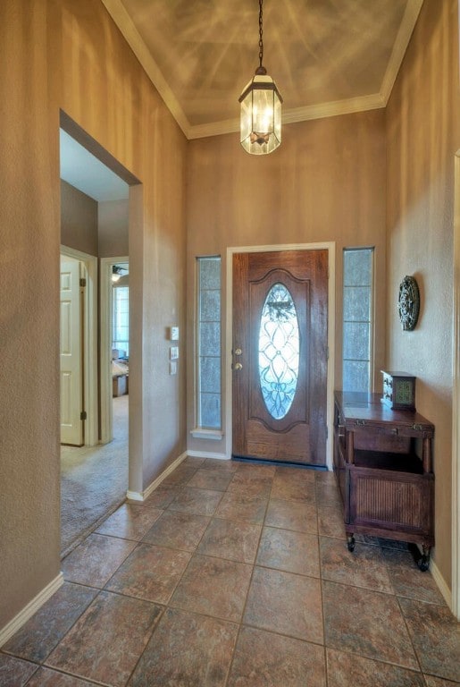 entryway with a notable chandelier, ornamental molding, and a high ceiling