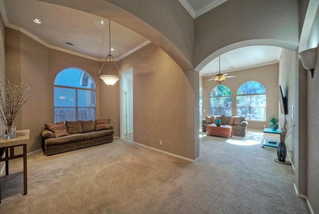 carpeted living room featuring ceiling fan, a towering ceiling, and ornamental molding