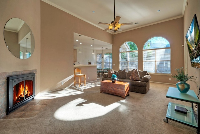 carpeted living room with ceiling fan, crown molding, and a fireplace