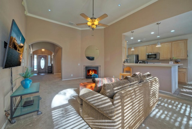 carpeted living room featuring ceiling fan, crown molding, and a fireplace