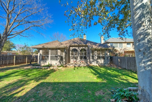 rear view of property featuring a yard and a sunroom