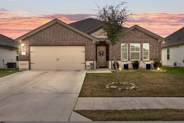 view of front of property featuring central AC unit, a garage, and a yard