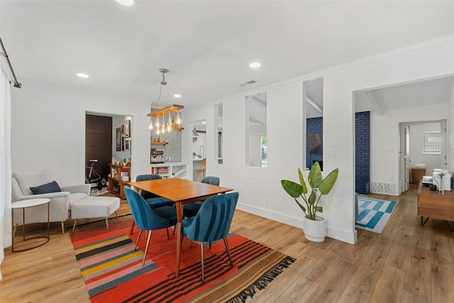 dining room with light hardwood / wood-style floors, an inviting chandelier, and crown molding