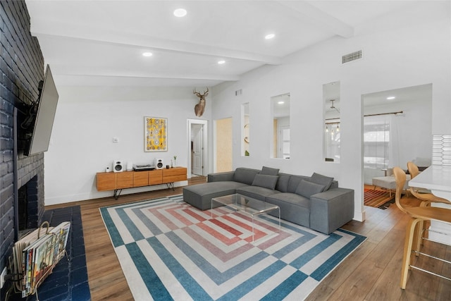 living room featuring hardwood / wood-style floors, beam ceiling, and a brick fireplace