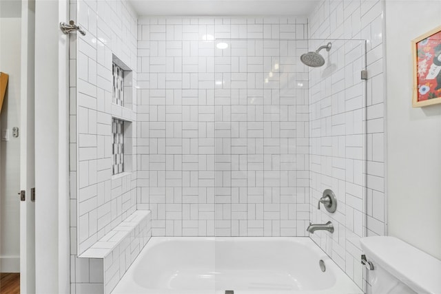 bathroom with tiled shower / bath combo and toilet