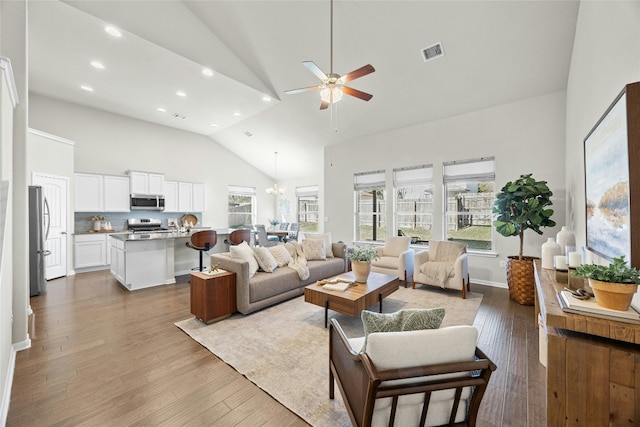 living room with hardwood / wood-style flooring, ceiling fan with notable chandelier, and high vaulted ceiling