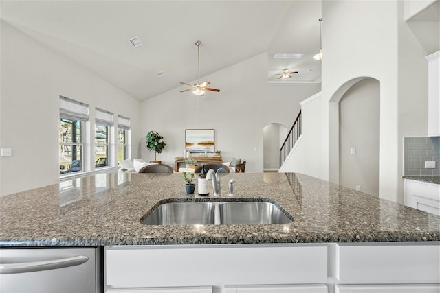 kitchen with backsplash, dark stone counters, sink, stainless steel dishwasher, and white cabinetry