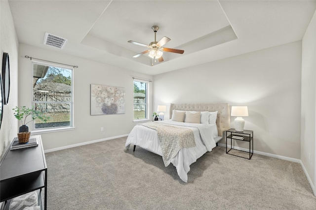 bedroom with ceiling fan, a raised ceiling, and light carpet