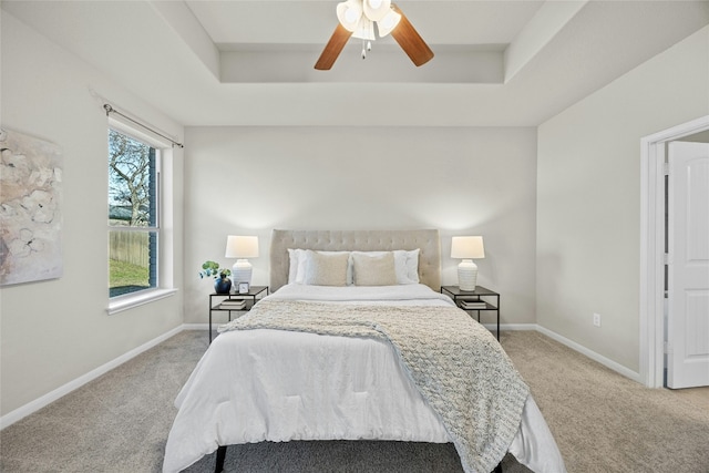 bedroom featuring a raised ceiling, ceiling fan, and carpet