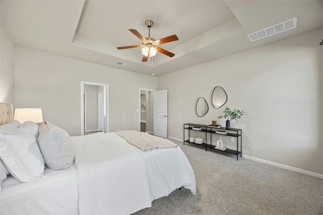 bedroom featuring carpet, a tray ceiling, and ceiling fan