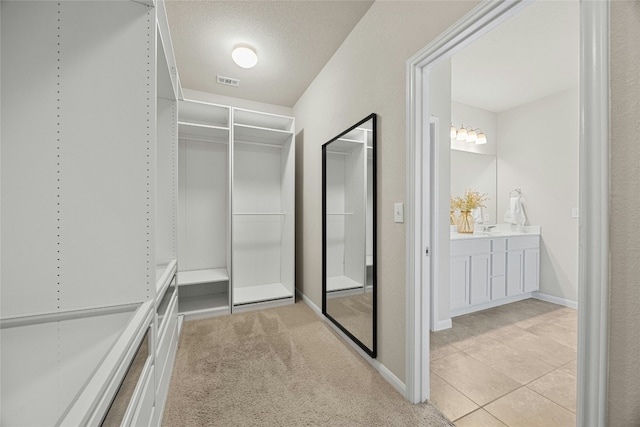 walk in closet with light tile patterned flooring and sink