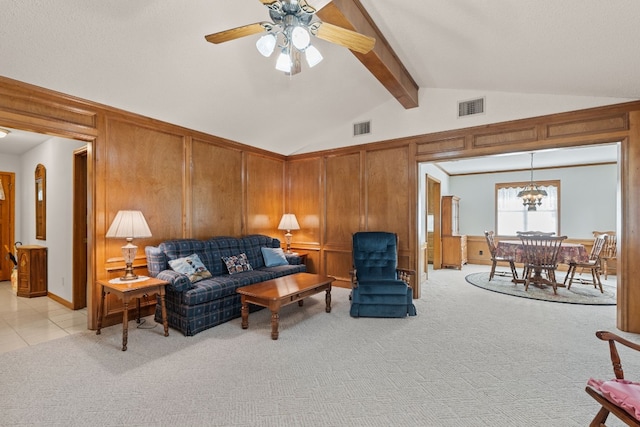 carpeted living room with ceiling fan with notable chandelier, lofted ceiling with beams, and wooden walls