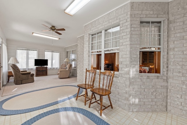 living room with ceiling fan, crown molding, and brick wall