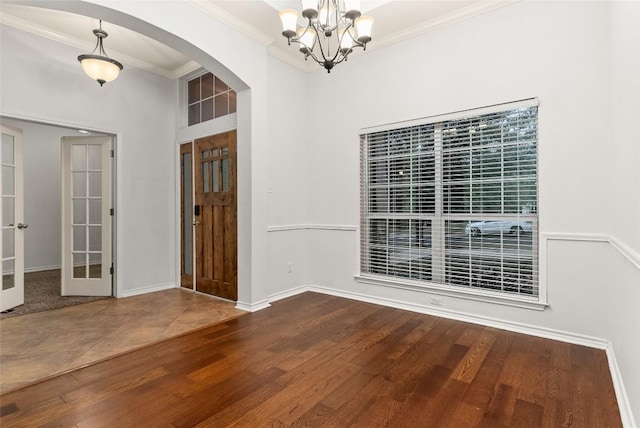 entrance foyer featuring hardwood / wood-style floors, a chandelier, ornamental molding, and french doors