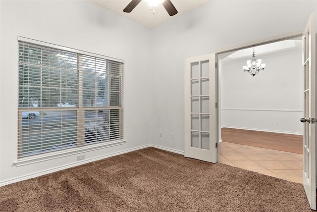 tiled empty room featuring french doors and ceiling fan with notable chandelier