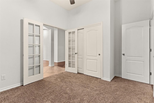 unfurnished bedroom featuring carpet, ceiling fan, a closet, and french doors