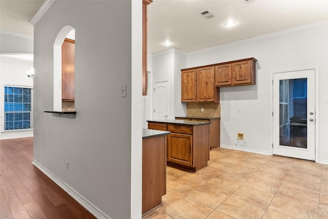 kitchen with backsplash, crown molding, and light tile patterned flooring