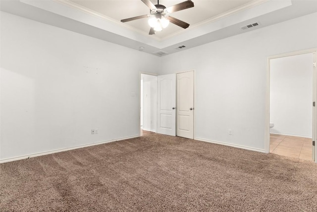 carpeted spare room featuring a tray ceiling, ceiling fan, and ornamental molding