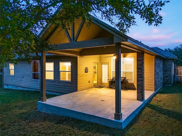 back house at dusk with a yard and a patio area