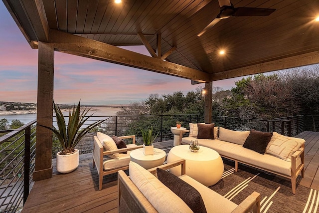 deck at dusk with a water view, ceiling fan, and an outdoor hangout area