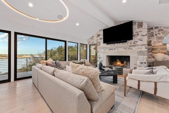 living room with light hardwood / wood-style flooring, a fireplace, lofted ceiling with beams, and plenty of natural light