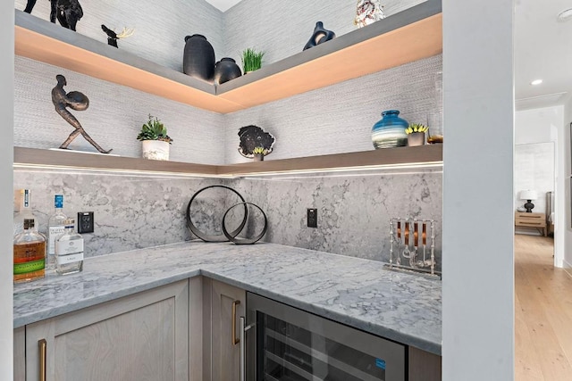 bar featuring light stone countertops, light hardwood / wood-style flooring, beverage cooler, and decorative backsplash