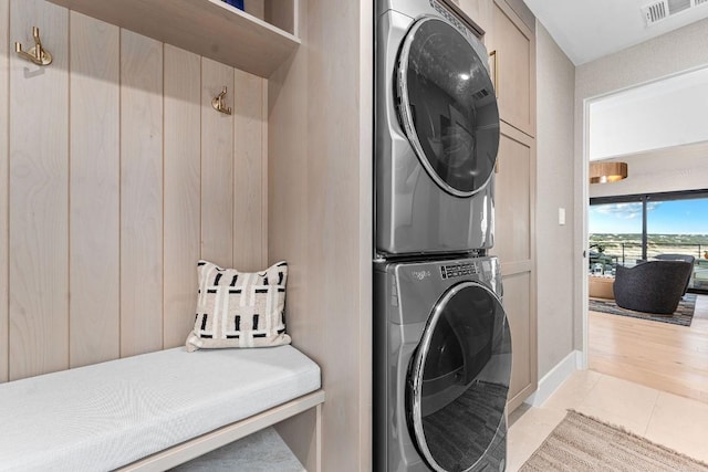 laundry area with light tile patterned flooring and stacked washer and clothes dryer