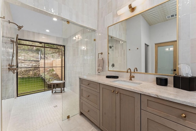 bathroom featuring vanity, tile walls, tile patterned floors, and walk in shower