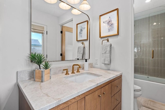 full bathroom featuring shower / bath combination with glass door, vanity, and toilet