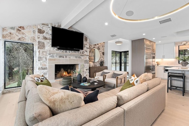 living room with a fireplace, light hardwood / wood-style flooring, and vaulted ceiling with beams