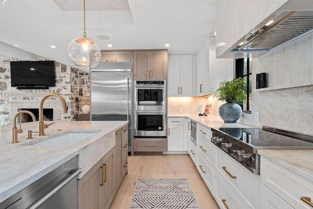 kitchen featuring stainless steel appliances, white cabinetry, light stone countertops, and sink