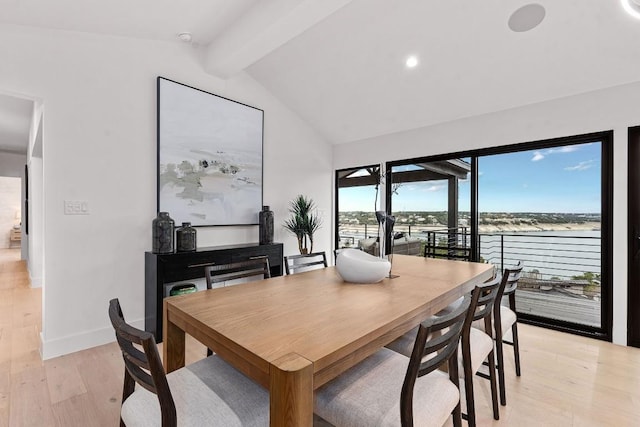 dining area featuring lofted ceiling with beams, a water view, and light hardwood / wood-style floors