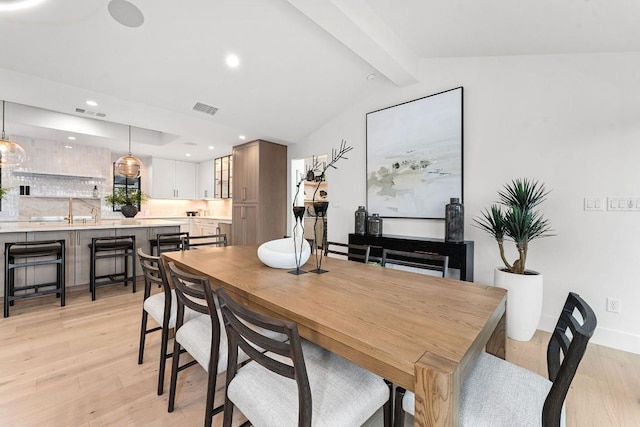 dining room featuring lofted ceiling with beams and light hardwood / wood-style floors