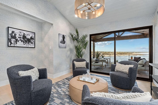 sitting room with hardwood / wood-style flooring, vaulted ceiling, a chandelier, and a water view