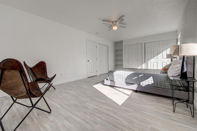 bedroom featuring two closets, light hardwood / wood-style flooring, and ceiling fan