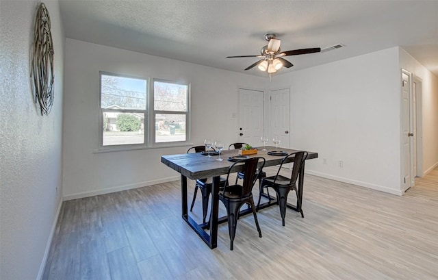 dining room featuring a textured ceiling, light hardwood / wood-style flooring, and ceiling fan