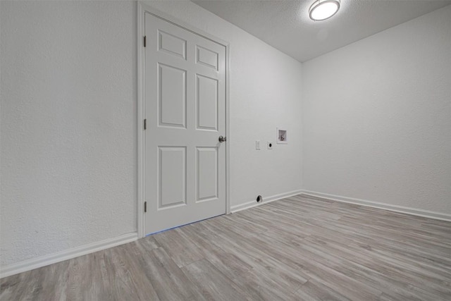 spare room featuring vaulted ceiling, a textured ceiling, and light hardwood / wood-style flooring