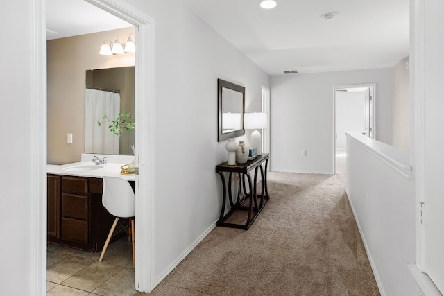 corridor featuring sink and light colored carpet