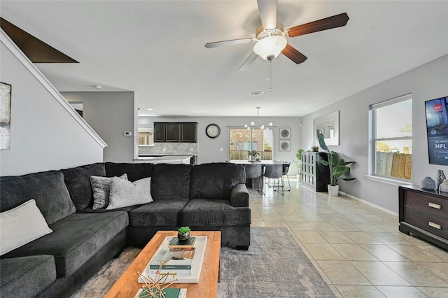 living room featuring light tile patterned floors and ceiling fan with notable chandelier