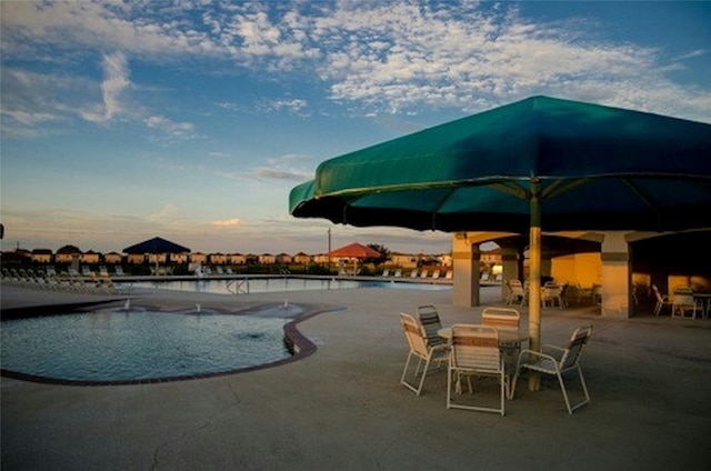 pool at dusk featuring a patio