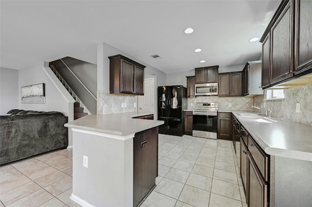 kitchen with dark brown cabinetry, sink, tasteful backsplash, light tile patterned floors, and appliances with stainless steel finishes