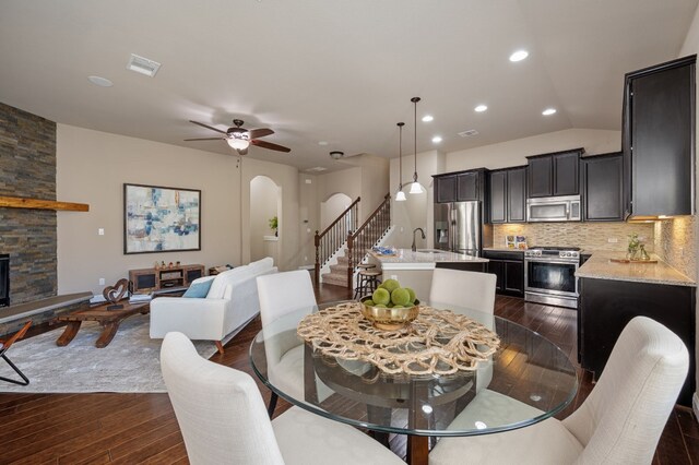 dining space with dark hardwood / wood-style floors, ceiling fan, a stone fireplace, and sink