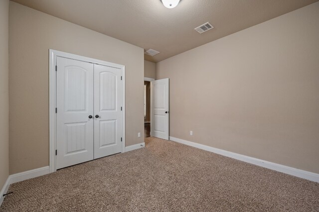 unfurnished bedroom featuring carpet flooring and a closet