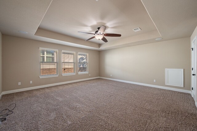 spare room with carpet, a tray ceiling, and ceiling fan